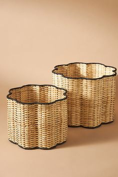 two wicker baskets with black rims sitting on a brown surface, one is empty