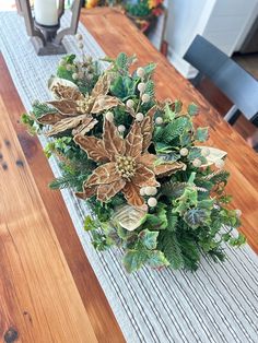 a christmas centerpiece on a dining room table with candles and greenery in the background