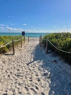 a sandy path leading to the ocean on a sunny day