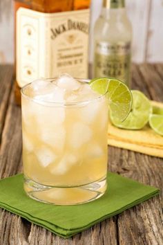 a glass filled with ice and lime sitting on top of a green napkin