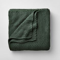 a green blanket folded on top of a white wall