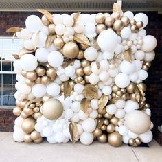 a large balloon wall with gold and white balloons on the front of a brick building