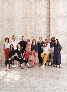 a group of people sitting and standing next to each other in front of a wall