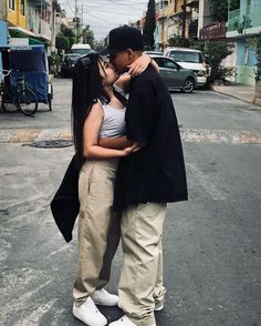 a man kissing a woman on the cheek while standing next to her in an empty street