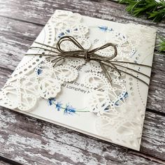 a white card with a bow on it and some string attached to the front, sitting on a wooden surface