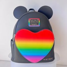 Mickey Mouse Pride Mini Backpack Colorful Rainbow Heart Disney Backpack *Part Of The Disney Pride Collection* Faux Leather Backpack With 3d Mickey Ears Big Rainbow Heart Front Pocket Fabric Lining With Mickey Mouse's Colorful Silhouettes Print Double Zipper Main Compartment Loungefly Logo Metal Pulls Silvertone Hardware Adjustable Padded Shoulder Straps Top Carry Handle Side Slip Pockets Disney Parks X Loungefly Rainbow Logo Label Plate Approximate 10 1/2'' H X 9'' W X 4 1/2'' D Authentic New Nw Black Backpack With Zipper For Disney Fan Events, Black Mickey Mouse Backpack For Disney Fan Events, Tiki Room Disney, Nightmare Before Christmas Backpack, Mickey Mouse Backpack, Mickey Mouse Balloons, Sequin Backpack, Grey Backpacks, Heart Pocket