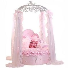 a pink canopy bed with a stuffed animal in it's center and netting on the sides