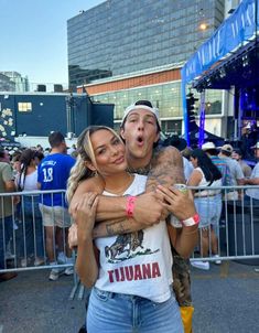 a man and woman hugging each other in front of a crowd at an outdoor event