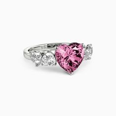 a pink heart shaped ring with three diamonds