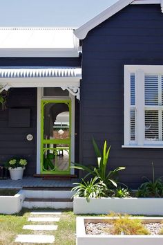 a blue house with white shutters and green front door is seen in this image