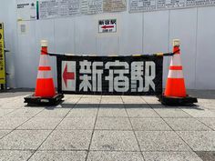 two orange and white cones sitting in front of a sign