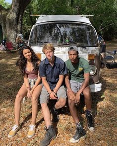 three people sitting on the back of a van