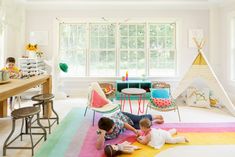 two children are laying on the floor in front of a teepee tent and table