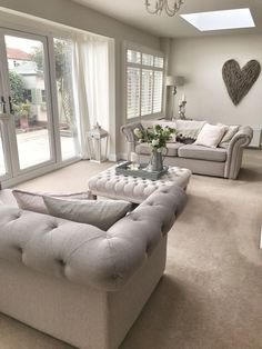 a living room filled with furniture and a chandelier hanging from the ceiling in front of two windows