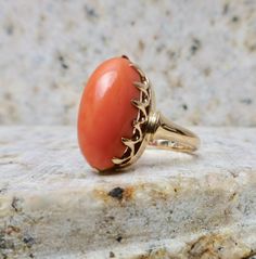 This amazing antique 10 karat, slightly rose gold, ring features a single, warm, salmon pink natural coral gemstone. It is hand cast with a charming basket mounting and dainty prongs. A truly fantastic piece of history dating back to the late Victorian and Edwardian era of, 1890-1915. Its ornate and beautiful face is set with a single, natural coral cabochon. The face of the ring measures 8.2mm by 15.2mm. The rise off the finger measures 8.8mm. The gold shows average wear to the surface and one Elegant Oval Coral Rings, Elegant Coral Ring Jewelry, Coral Oval Jewelry For Weddings, Elegant Coral Rings For Anniversary, Elegant Coral Oval Rings, Classic Round Coral Jewelry, Classic Coral Round Jewelry, Formal Coral Ring, Coral Elegant Wedding Rings