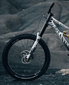 a white and black mountain bike parked on the side of a rocky hill with mountains in the background