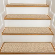 a set of stairs with beige carpet and wooden treads in a white walled room