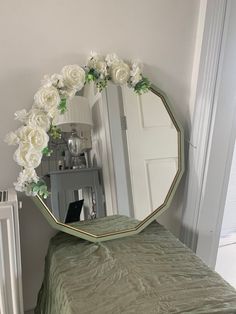 there is a mirror with flowers on it in the corner next to a small bed