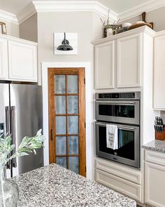 a kitchen with white cabinets and granite counter tops, stainless steel appliances and an open door