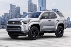 a silver toyota pickup truck parked in front of a city skyline