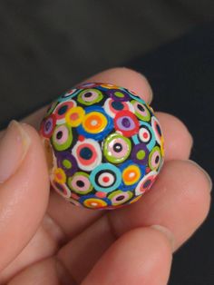 a hand holding a colorful ball in it's palm