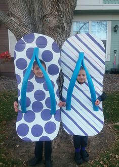 two young boys standing next to each other in front of a tree holding surfboards