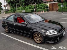 a black car with gold rims parked in a parking lot