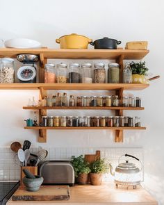 the shelves above the kitchen counter are filled with spices and other things to cook in