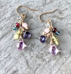 "Gemstone Dangle Earrings Cluster Earrings in Gold Fill Pink amethyst briolettes drop from shimmering gold fill, accompanied by a glorious cluster of tiny gemstones: Garnet, Iolite, Peridot, Rose Quartz, Fluorite, and London Blue Topaz. Lavishly wrapped in gold-filled wire, the genuine gemstones twinkle and sparkle fetchingly. Wire-wrapped to a paperclip link gold-filled chain, the earrings dangle from ball-tipped earring wires. Also available in lever back earring wires, which snap shut for gre Multicolor Dangle Earrings With Gemstone Accents, Multi-stone Dangle Earrings For Party, Multicolor Gemstone Accented Drop Earrings, Dangle Multi-stone Earrings For Gifts, Multi-stone Long Drop Jewelry Gift, Gold Multi-stone Dangle Jewelry, Dangle Jewelry With Natural Stones For Parties, Dangle Crystal Earrings With Gemstone Accents As Gift, Ear Art