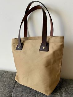 "Our leather-canvas tote bag is handcrafted to carry anything you care about. We've worked hard to make this a lightweight, easy to clean every day bag that's as elegant as it's functional. It features a top entry that can fit all your everyday essentials including a 15\" laptop or a tablet, and an nside pocket for small item storage.  Materials:  ~ 20 oz Waxed cotton-twill canvas - that will keep all your items safe and dry in any weather conditions.   ~ Full-grain bridle leather straps - meant Casual Waxed Canvas Tote Bag, Casual Double Handle Waxed Canvas Bag, Everyday Duck Canvas Tote Bag, Everyday Waxed Canvas Bag, Waxed Canvas Tote Bag For Everyday Use, Khaki Canvas Tote Bag For Everyday, Waxed Finish Canvas Tote Bag For Everyday Use, Rectangular Duck Canvas Bag For Everyday Use, Everyday Waxed Finish Canvas Tote Bag