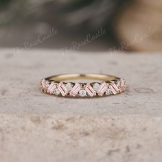 a pink and white diamond ring sitting on top of a stone