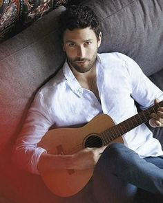 a man sitting on top of a couch holding a guitar