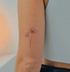 a woman's arm with a single flower tattoo on the left side of her arm