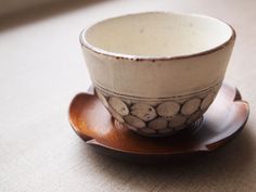 a white and brown cup sitting on top of a wooden saucer