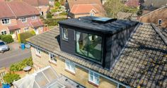 an aerial view of a house with solar panels on the roof, and other houses in the background