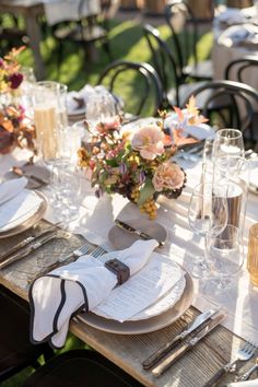 the table is set with silverware, plates and flowers in vases on it