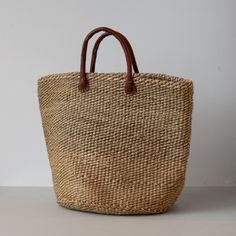 Sisal is a flowering plant that has been cultivated and naturalized in Kenya, and the strong fibers that come from it are used to make various items from rope to bags. These durable baskets can handle a heavy load without breaking a sweat while looking handsome at the same time! Woven from natural sisal plant fibers with leather handles. A Kenyan market artisan partnership. Learn more about our artisans' handmade products here. Details: Approximately 14" T 20" W Large Approximately 12" T 18" W Medium Colors and designs vary due to the handmade nature of this product Not eligible for free shipping Neutral Bucket Bag With Braided Handles, Neutral Bucket Bags With Braided Handles, Nature-inspired Rectangular Bag For Daily Use, Everyday Nature-inspired Rectangular Bag, Nature-inspired Everyday Rectangular Bag, Everyday Neutral Handwoven Straw Bag, Everyday Beige Bags Made Of Natural Fiber, Everyday Beige Bag In Natural Fiber, Everyday Beige Bags In Natural Fiber