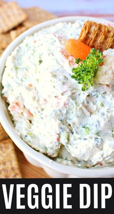 a white bowl filled with veggie dip next to crackers and carrots