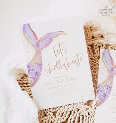 two mermaid themed wedding cards sitting on top of a wicker basket next to a white blanket