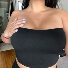 a woman in a black top with blue nails holding her hand up to her chest