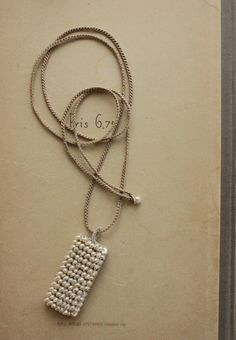 a white beaded necklace with a silver chain