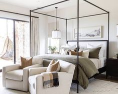 a bedroom with four poster bed, chair and ottoman in front of sliding glass doors