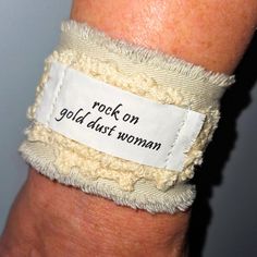 For A Boho Gypsy Wardrobe Hippie Cloth/Fabric Cuff Bracelet Stevie Nicks, Fleetwood Mac Song Lyrics From The Rumors Album "Rock On Gold Dust Woman" A Thoughtful & Personalized Music Lovers Gift! ***Adjustable, Durable & Possibly The Most Comfortable Bracelet You'll Ever Own! Eco Friendly & Sustainable Text Is Heat Set & Water Resistant Cleans With A Wet One Or Machine Wash Upcycled Sandstone Beige Fabric With Gray Backing Accented With Vintage Crochet Frayed Edges Closes With A Vintage Button & Adjustable Wristband For Festivals, Adjustable Cream Cuff Bracelet Gift, Adjustable Cream Cuff Bracelet As Gift, Adjustable Cream Cuff Bracelet For Gift, Handmade Trendy Cuff Bracelet For Festivals, Trendy Handmade Cuff Bracelet For Festivals, Bohemian White Wristband For Festivals, Rock On Gold Dust Woman, Sandstone Beige