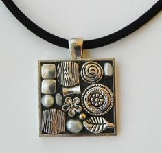 a silver square pendant on a black cord