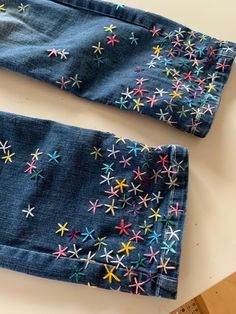 two pairs of blue jeans with multicolored stars on them