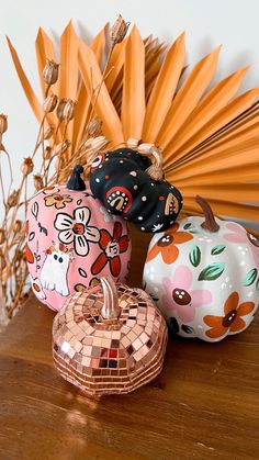 three decorative pumpkins sitting on top of a wooden table