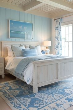 a white bed sitting in a bedroom on top of a blue and white rug next to a window