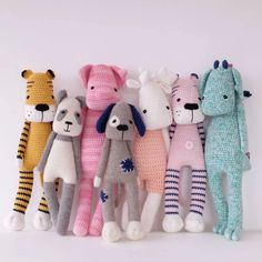 five crocheted stuffed animals lined up against a white wall, all in different colors