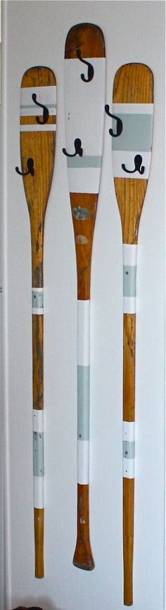 three wooden baseball bats with faces drawn on them, lined up against a white wall