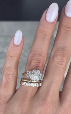 a woman's hand with three different rings on her fingers and one ring in the middle